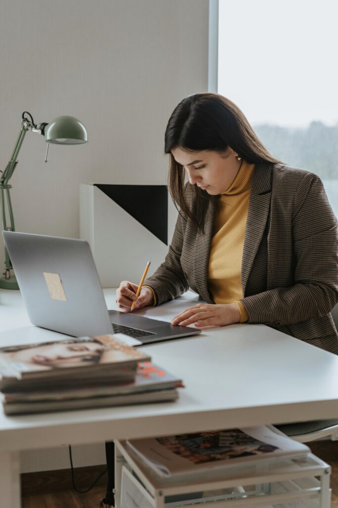 Kobieta analizująca dokument przy biurku z laptopem – symbol spokoju, kontroli i działania w sprawie cesji wierzytelności.